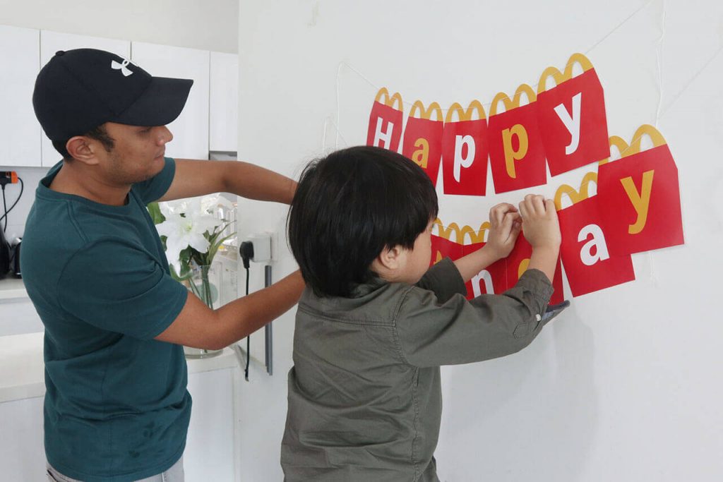 ayah dan anak menghias dinding untuk sambutan hari jadi bersama McDonald's