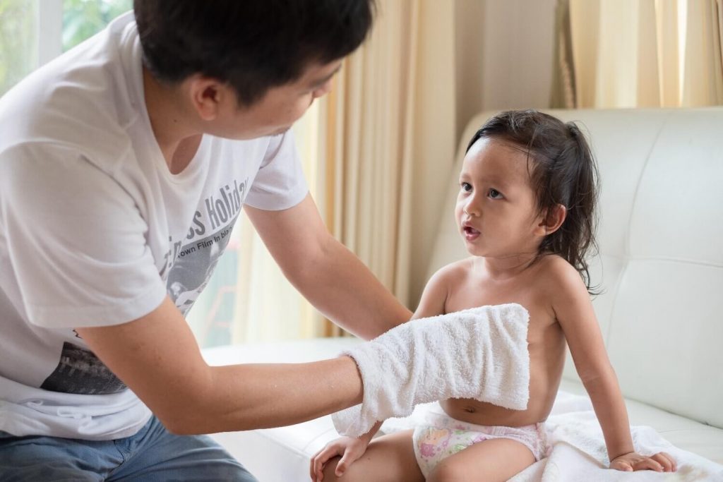 ayah lap badan anak perempuan selepas dimandikan dengan air sejuk 