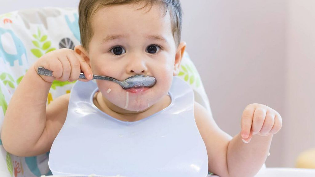 bayi sedang menikmati makanan bayi 1 tahun