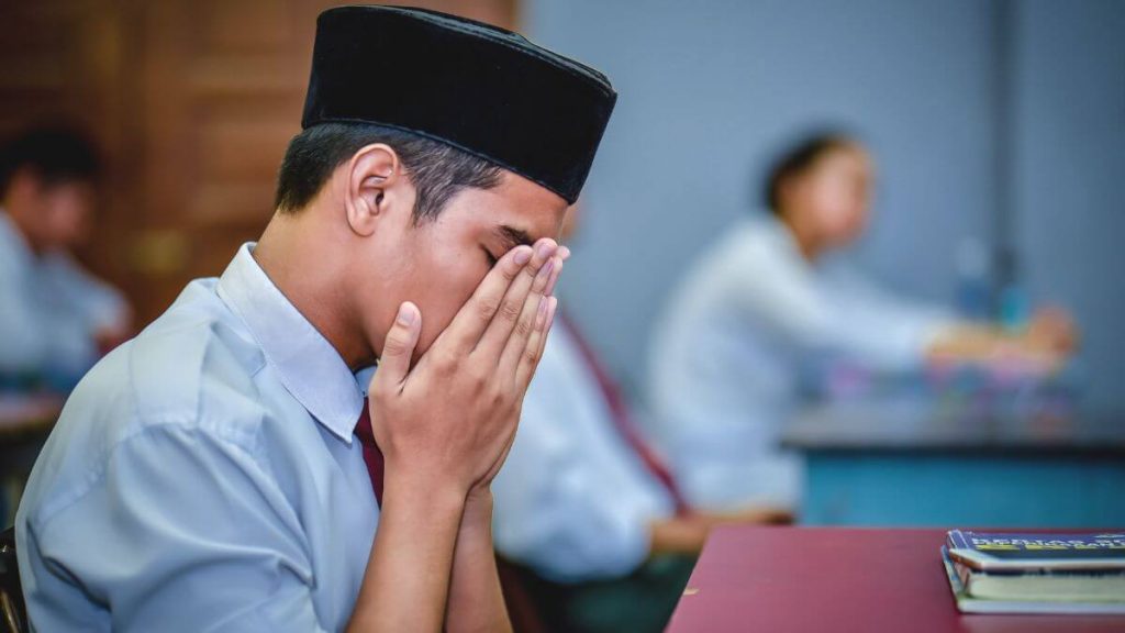 pelajar lelaki mengaminkan doa sebelum belajar