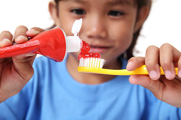 kanak-kanak meletakkan ubat gigi pada berus gigi