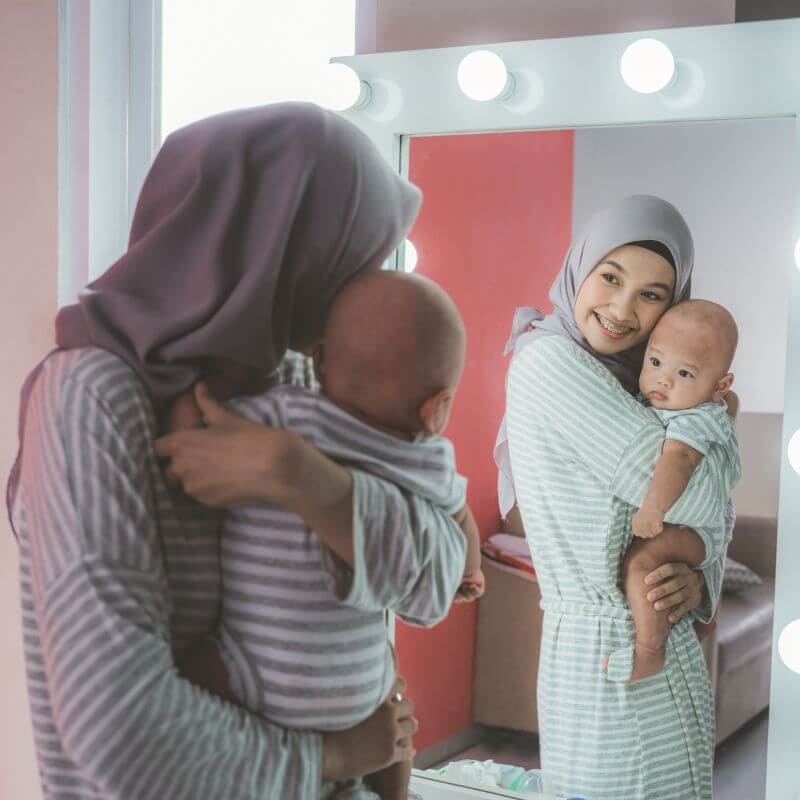 wanita dan bayi di hadapan cermin sambil membaca doa melihat cermin