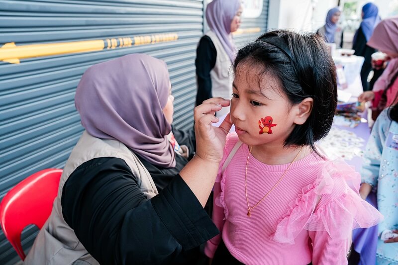 kanak-kanak mendapatkan stiker muka di Karnival FunSTEM ALFA and Friends