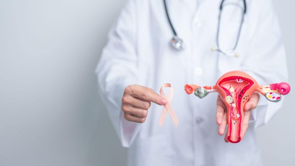 doctor holding peach ribbon with uterus ovaries model september uterine canc