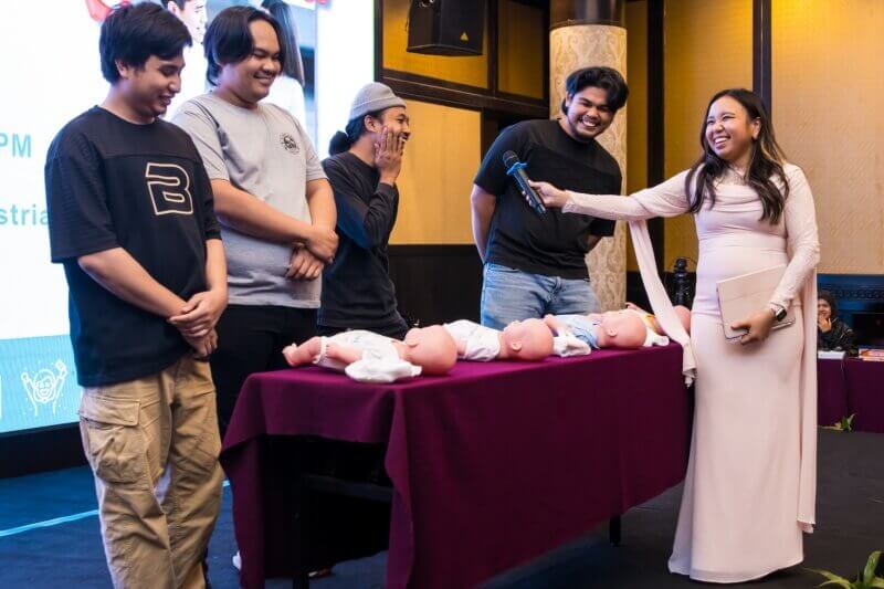 Bakal ayah bersama Host mencuba pakaikan lampin bayi di kelas Parentcraft yang disokong oleh Tourism Malaysia – Visit Malaysia 2026: Malaysia Truly Asia