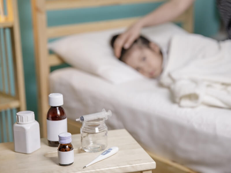 Influenza Kanak-kanak - anak demam, dimeja ada termometer dan ubat demam